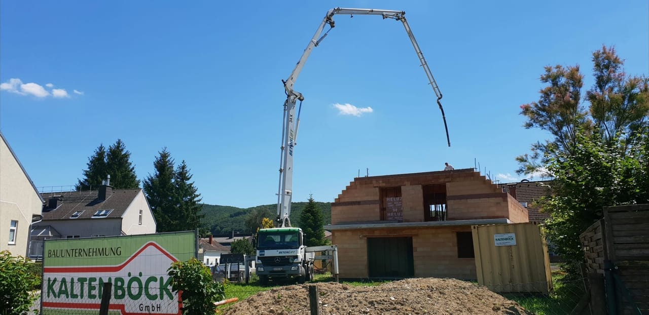 Foto: Rohbau mit Betonpumpe und Bautafel